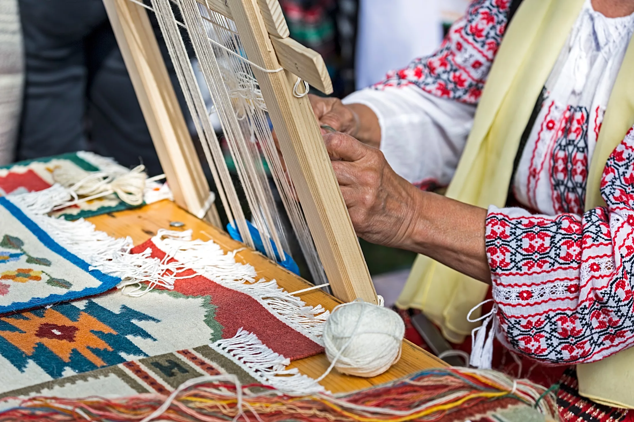 Hands of woman who weave traditionally at one small loom and made various models with hand.
