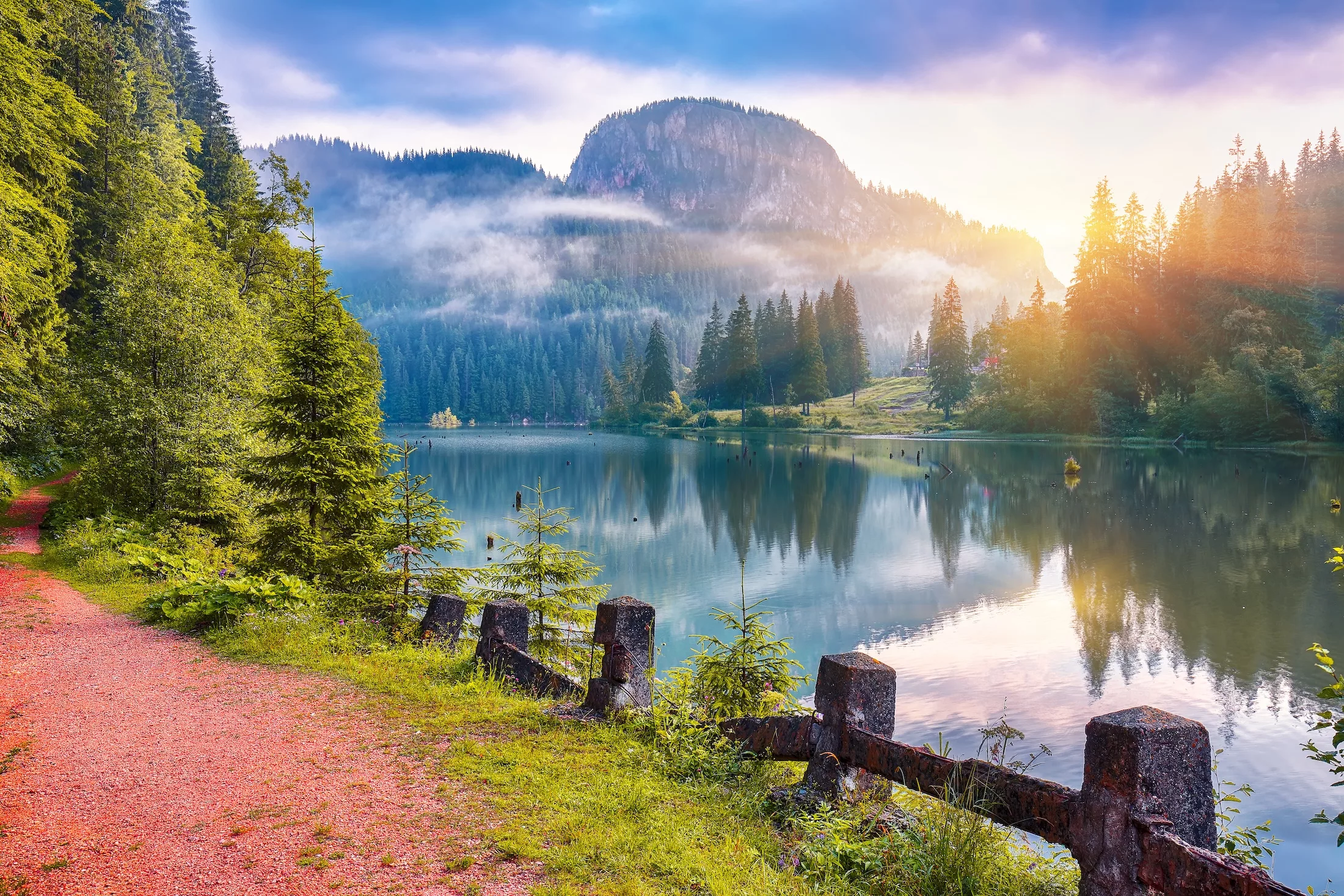 Majestic summer view of mountain lake Lacul Rosu or Red Lake or Killer Lake. Rotten tree trunks. Logs coming out of the water. Harghita County, Eastern Carpathians, Romania, Europe