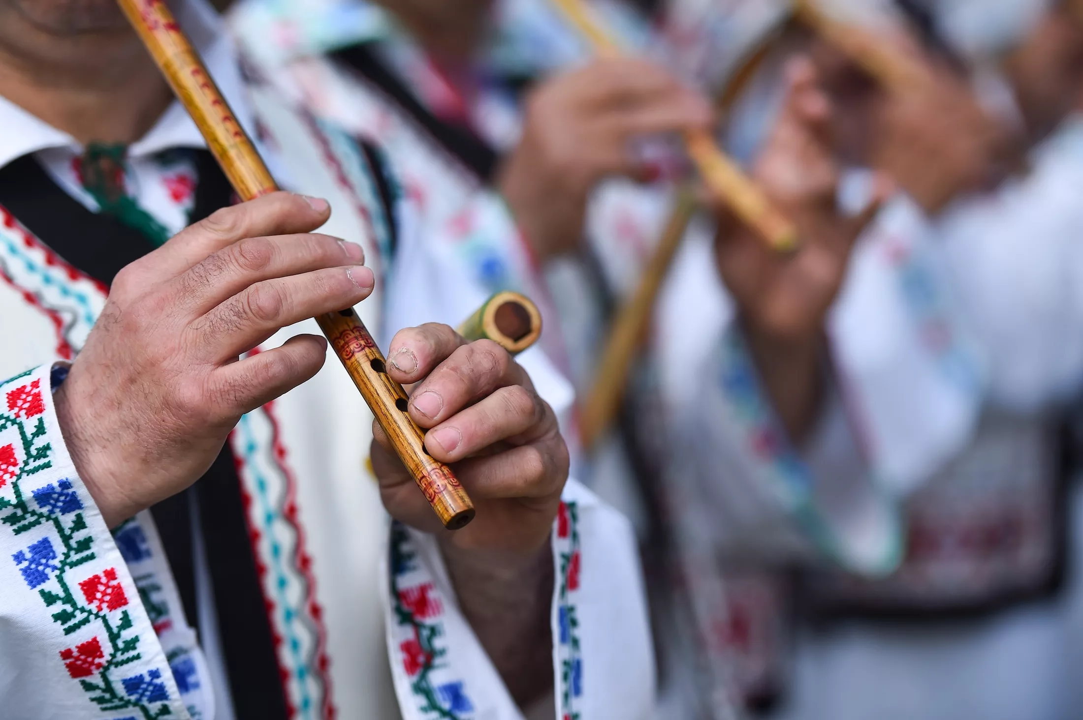 People in romanian traditional costumes singing at wooden flutes